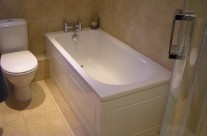 New bath with Nabis Nero taps, solid bath panels and natural tiles